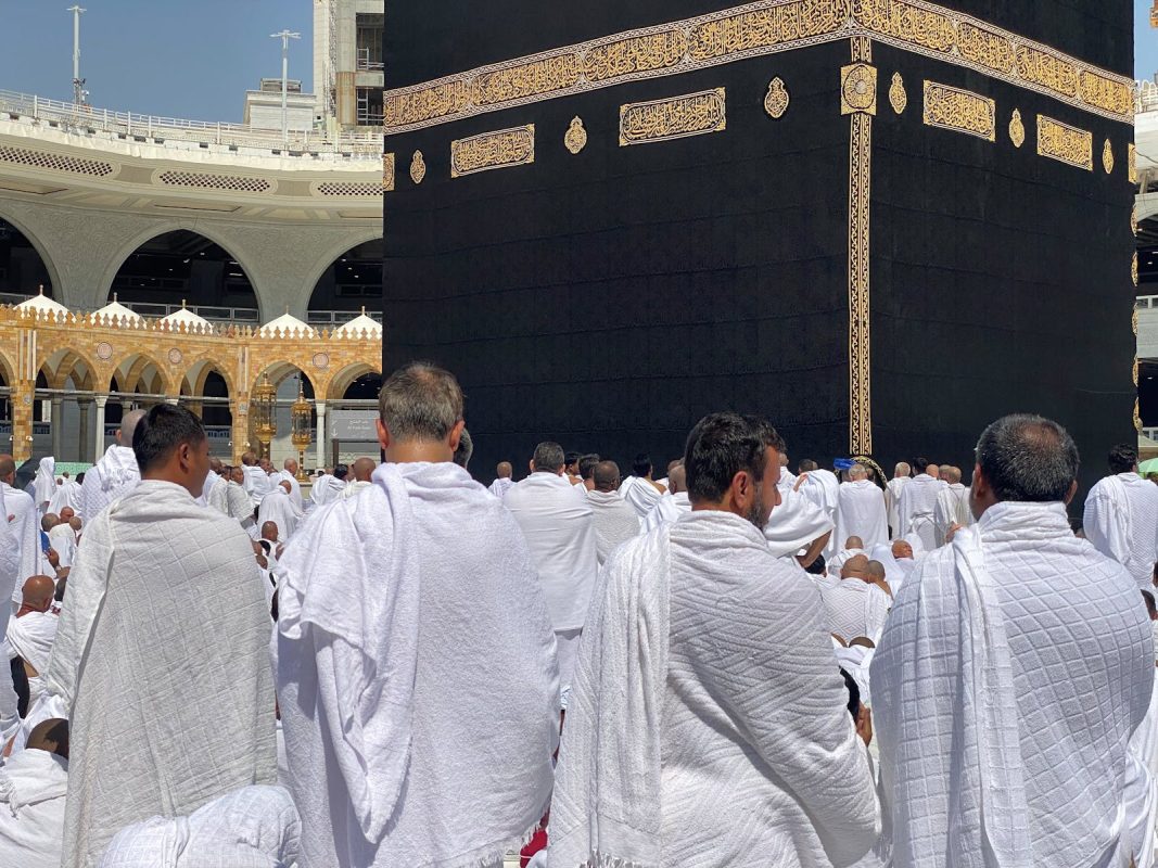 A large group of Muslim pilgrims in white garments gathered around the Kaaba in Mecca. Spirituality and devotion in Saudi Arabia.