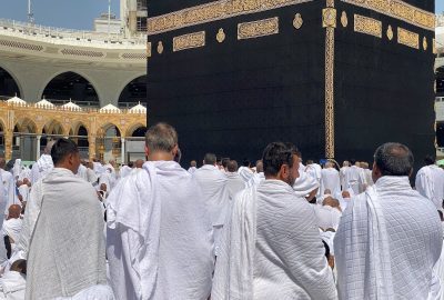 A large group of Muslim pilgrims in white garments gathered around the Kaaba in Mecca. Spirituality and devotion in Saudi Arabia.