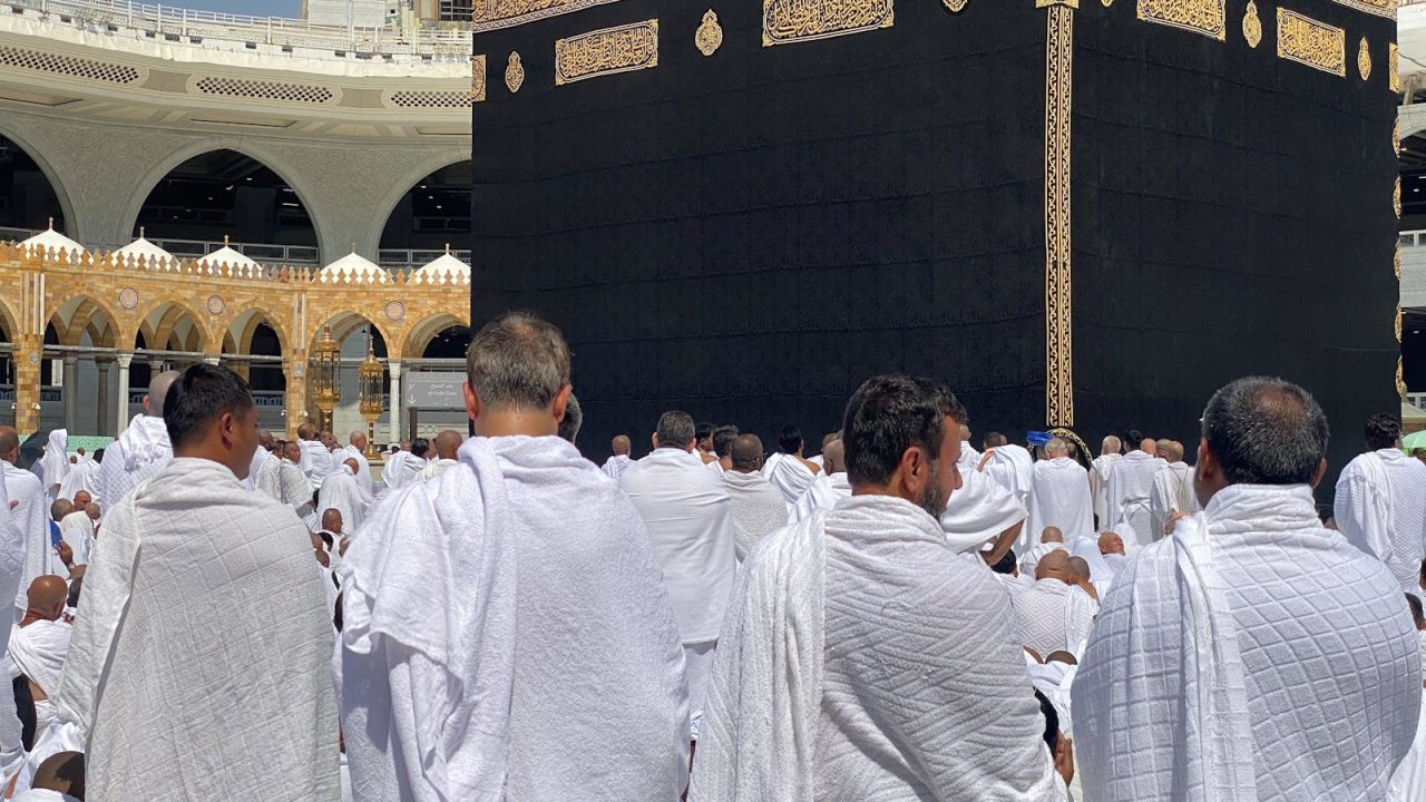 A large group of Muslim pilgrims in white garments gathered around the Kaaba in Mecca. Spirituality and devotion in Saudi Arabia.